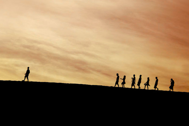 line of people following a man up a hill